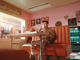 주황색 소파에 앉아 여유롭게 차를 마시는 아티스트 크러쉬와 LG 휘센 시스템 에어컨